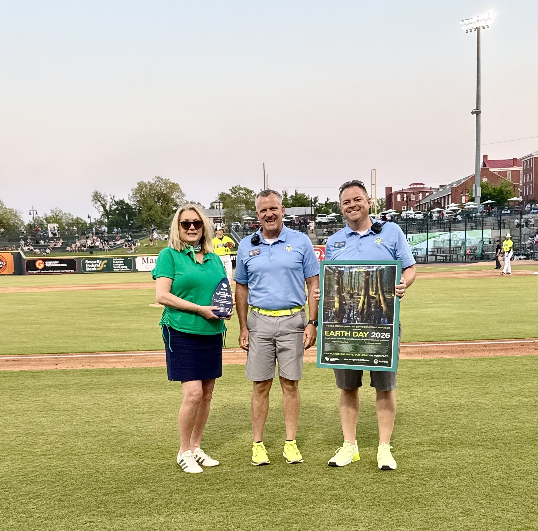SCDES Director Myra Reece presents the agency’s Power of Partnerships Award to representatives of the Columbia Fireflies during an on-field presentation at Segra Park on Earth Day