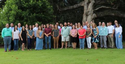 large group of people posing for a photo outside on green grass