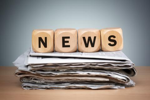 Newspapers folded and stacked with the word news in wooden block puzzle dice 