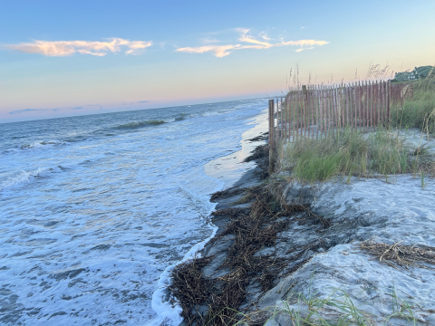 A photo of an eroded beach shoreline at high tide.
